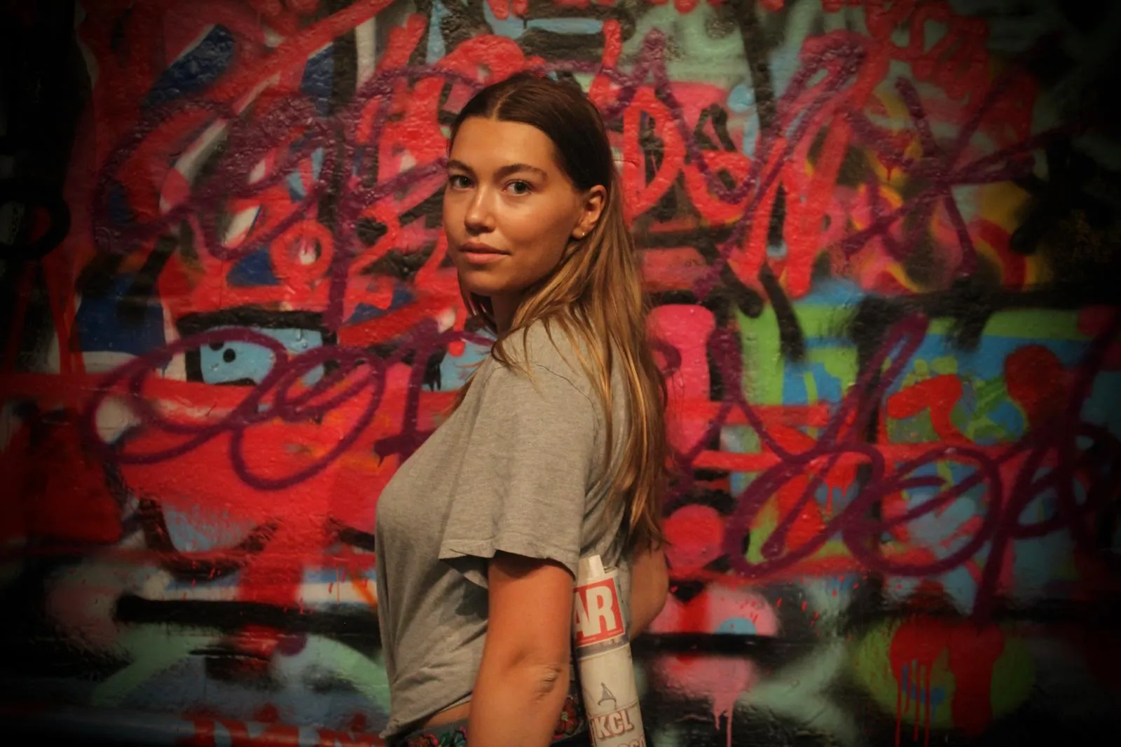 Lily Fairbank standing in front of a wall of red and purple graffiti