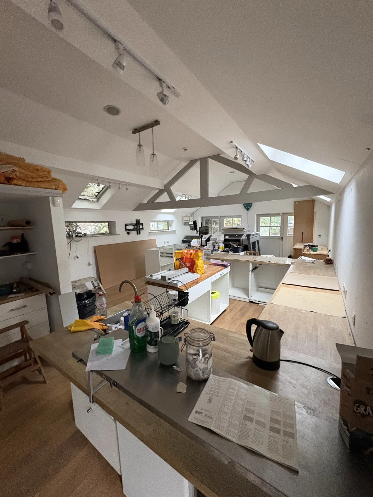 The main room before work: a pitched ceiling with skylights, worktops, printers and clutter